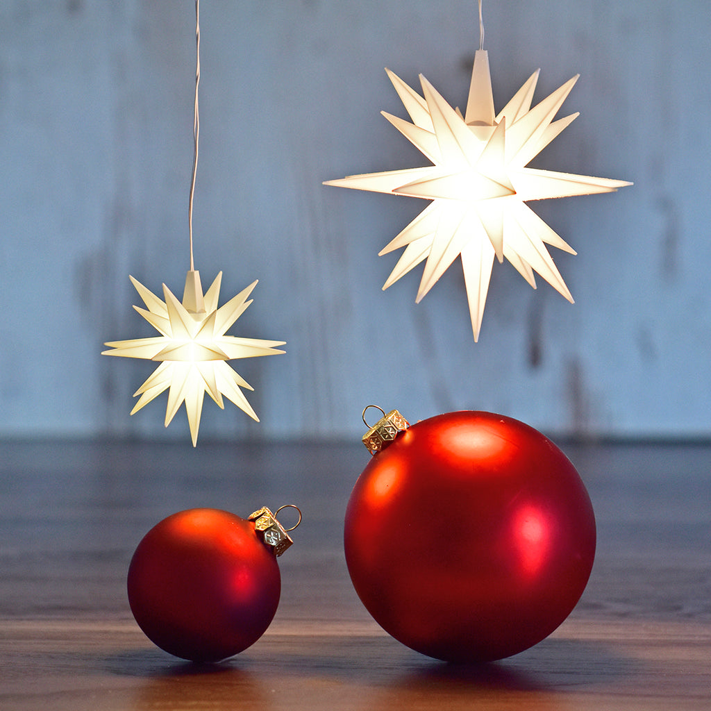 liten julstjärna vit hängandes över röda julkulor